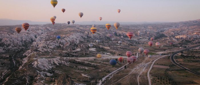 Decenas de coloridos globos aerostáticos se deslizan sobre los singulares valles y chimeneas de hadas de Capadocia en las primeras horas de la mañana.