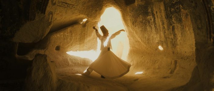 Un derviche mevleví realizando una danza derviche giratoria dentro de una iglesia rupestre histórica en Capadocia.