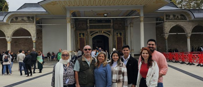 Un grupo de siete turistas sonríen y posan frente a la histórica Babüssaade (Puerta de la Felicidad) en el Palacio Topkapi de Estambul.