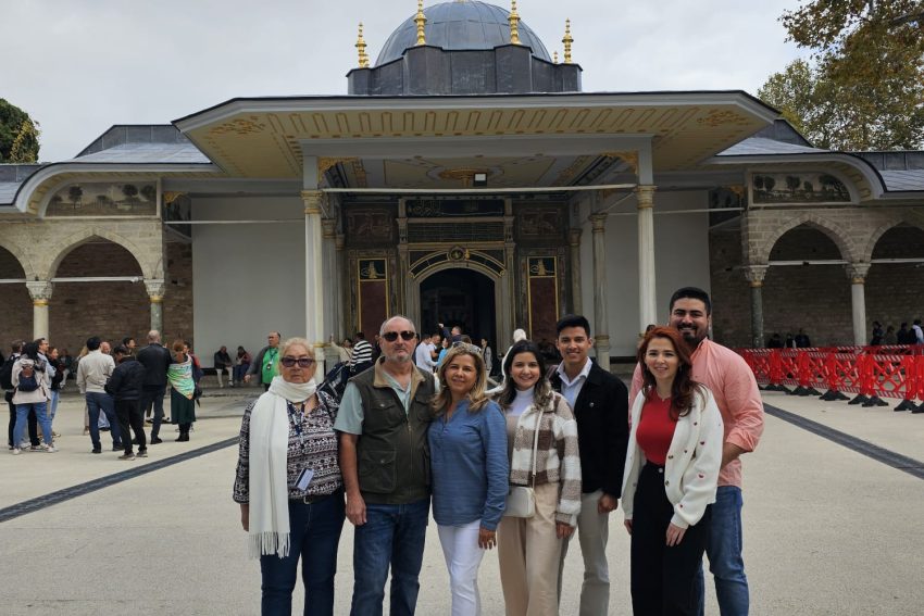 Un grupo de siete turistas sonríen y posan frente a la histórica Babüssaade (Puerta de la Felicidad) en el Palacio Topkapi de Estambul.