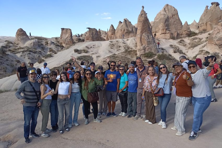 WhatsApp Image 2024-12-31 at 09.06.01 Una experiencia inolvidable en el valle de Devrent, en Capadocia. Un grupo de visitantes disfrutando de la atmósfera mágica de las chimeneas de hadas con un guía profesional. Una foto de recuerdo de Capadocia, patrimonio cultural y maravilla natural de Turquía.