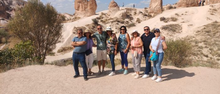 Un grupo de ocho turistas posando uno al lado del otro frente a la famosa chimenea de hadas con forma de camello en el valle de Devrent, en Capadocia.