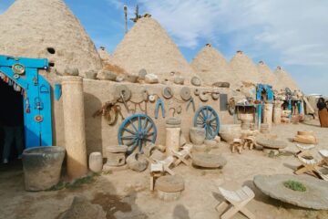 Casas de Harran y herramientas agrícolas tradicionales; arquitectura auténtica de casas de pueblo con alto contraste y colores vibrantes.